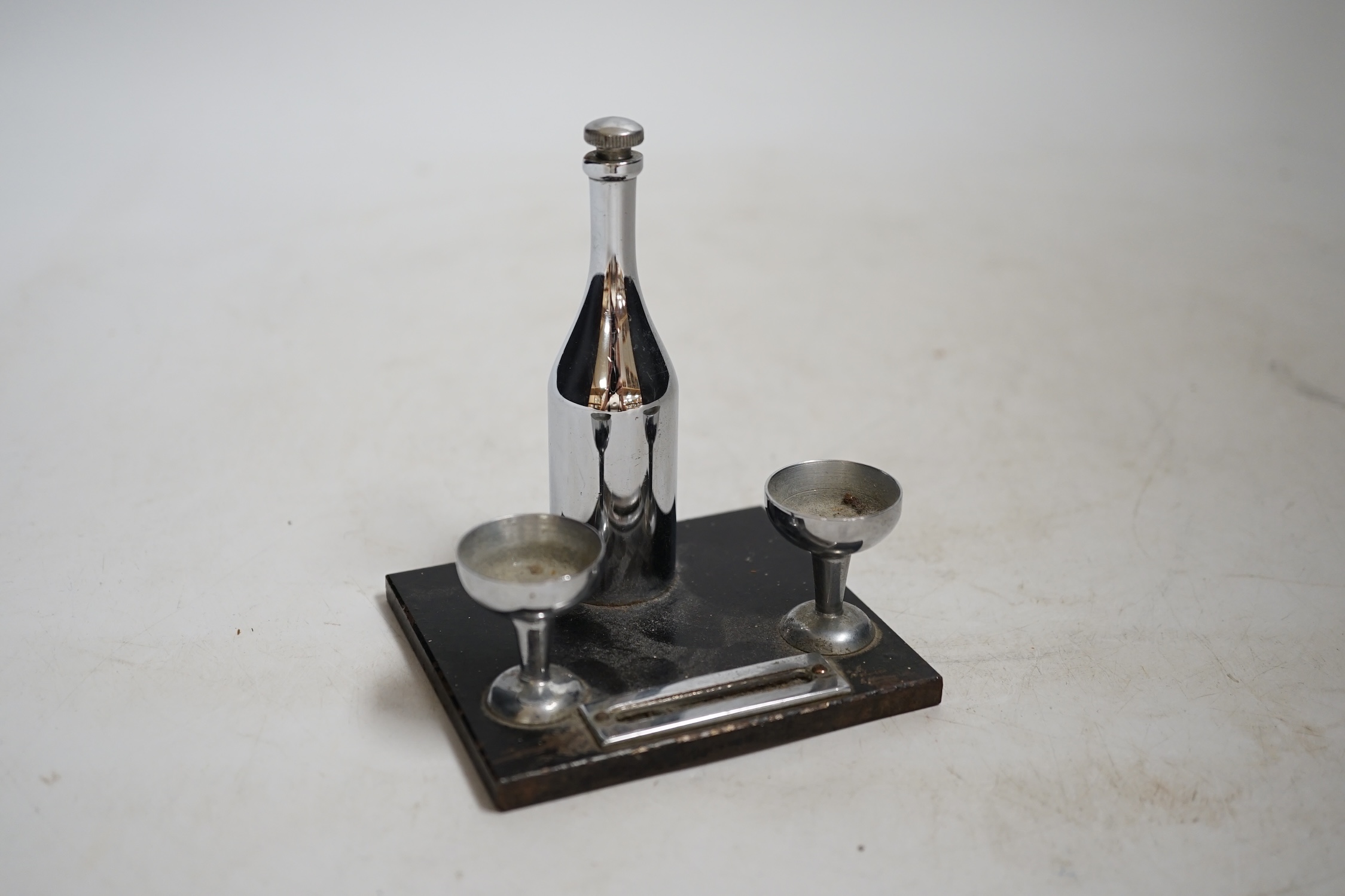 Two Art Deco match strikes, one in the form of a champagne bottle and two glasses, largest 13cm wide. Condition - fair